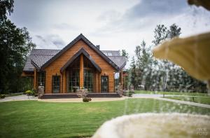 een huis met een groen gazon ervoor bij Villa Avirio Vingis in Druskininkai