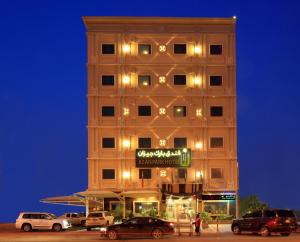 a tall building with cars parked in front of it at Park Jizan Hotel in Jazan