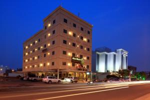 a building with cars parked in front of a street at Park Jizan Hotel in Jazan