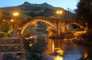 uma velha ponte de pedra sobre um rio à noite em Hotel La Alfonsina em Santibáñez de Villacarriedo