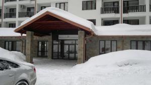 un edificio cubierto de nieve con un coche aparcado delante en Borovets Holiday Apartments - Different Locations in Borovets, en Borovets