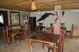 un comedor con mesas de madera y un delfín en la pared en Tambuti lodge en Rundu