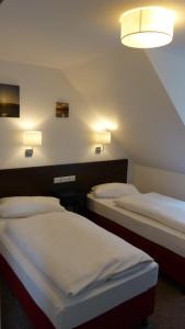 two beds in a room with two lights on the wall at Appartements am Schaalsee in Zarrentin