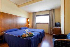 Habitación de hotel con cama y bandeja de fruta. en Hotel Galaico, en Collado-Villalba