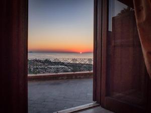 サント・ステーファノ・ディ・カマストラにあるGuest House a Portapalermoの夕日の海の景色を望むオープンドア