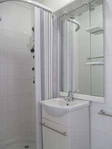 ein weißes Badezimmer mit einem Waschbecken und einem Spiegel in der Unterkunft Guesthouse da Sé in Guarda