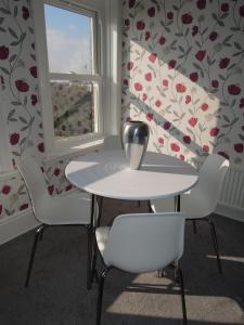 una mesa y sillas blancas en una habitación con ventana en Special seafront apartment, en Portsmouth