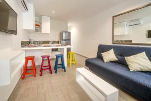 a living room with a blue couch and colorful stools at Valentina Suites by Las Flores Vacation Rentals in Playa del Carmen