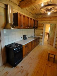 Il comprend une cuisine équipée d'une cuisinière noire et de placards en bois. dans l'établissement Pinnamäe Holiday House, à Partsi