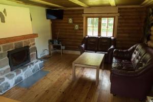 a living room with leather furniture and a fireplace at Pinnamäe Holiday House in Partsi