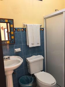La salle de bains est pourvue de toilettes blanches et d'un lavabo. dans l'établissement El Tucan, à Puerto Escondido