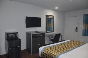 a hotel room with a bed and a desk and a television at Travelers Inn in Rosenberg