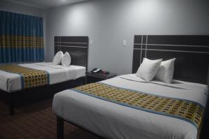 a hotel room with two beds and a phone at Travelers Inn in Rosenberg