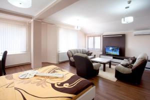 uma sala de estar com um sofá e cadeiras e uma televisão em Guesthouse Vitez em Vranje
