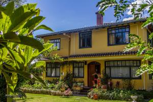 a yellow house with black windows and plants at Hostal Saint Mary´s Tababela in Tababela
