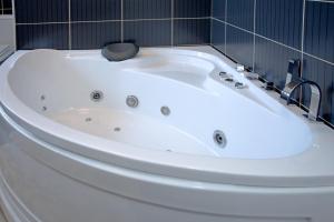 uma banheira branca na casa de banho com azulejos pretos em Guesthouse Vitez em Vranje