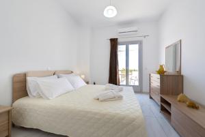 a white bedroom with a large bed and a dresser at Sun View Villas in Pirgos