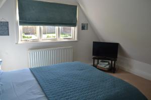 1 dormitorio con 1 cama y TV de pantalla plana en Appletree Cottages, en Mildenhall