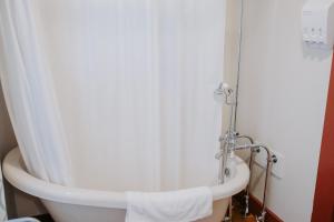 La salle de bains est pourvue d'une baignoire avec un rideau de douche blanc. dans l'établissement Maison Mouton Bed & Breakfast, à Lafayette