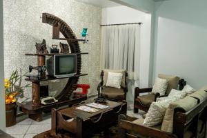 uma sala de estar com um sofá e uma televisão em Pousada Casarão em Jaraguá do Sul
