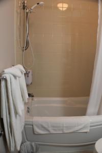 a bathroom with a tub and a shower with towels at Auberge - Village Grande Nature Chic-Chocs in Cap-Chat