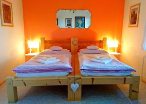 two beds in a room with an orange wall at Penzion Bor in Náchod