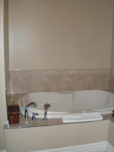 a bath tub with two faucets and a sink at Spanish Bay Inn, CANADA in Sydney