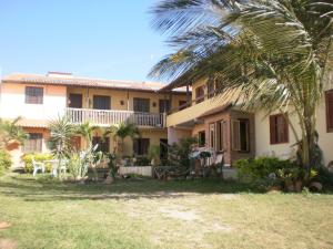 a building with a palm tree in front of it at Suites do Peró in Cabo Frio