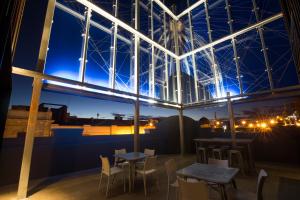 a rooftop patio with tables and chairs at night at Quest Fremantle in Fremantle