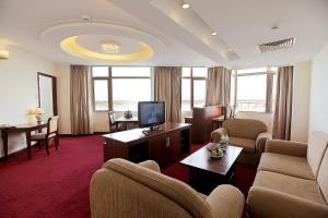 ein Hotelzimmer mit einem Sofa, Stühlen und einem TV in der Unterkunft Sai Gon Phu Yen Hotel in Tuy Hoa
