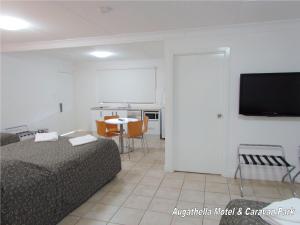 um quarto com uma cama, uma mesa e uma televisão em Augathella Motel & Caravan Park em Augathella