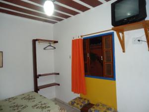 een kamer met een bed en een tv aan de muur bij Flores de Búzios Suítes in Búzios