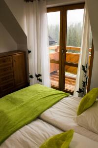 a bedroom with a bed with a large window at Cichy Domek in Małe Ciche