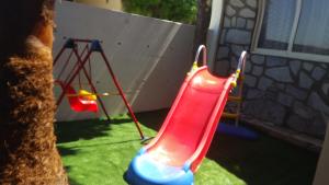 a toy slide in a yard with a swing at Villa Galleria in Perivolia