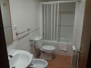 a white bathroom with a toilet and a sink at Hospedería Prepirineo in Undués-Pintano