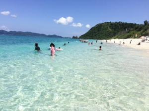 a group of people in the water at a beach at Little Asia Guest House in Naha