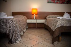 a room with two beds and a lamp on a table at Albergo Diffuso Zoncolan in Ovaro