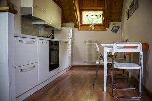 une cuisine avec des appareils électroménagers blancs, une table et un tabouret dans l'établissement Albergo Diffuso Zoncolan, à Ovaro