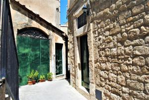 un vecchio edificio con una porta verde e piante in vaso di Modica View a Modica