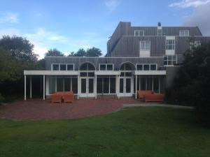 een groot gebouw met oranje stoelen ervoor bij Kaapshoff 32 in Hollum