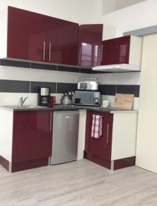 a kitchen with red and white cabinets and appliances at Appartement T1 Hyper Centre place de la Victoire in Bordeaux