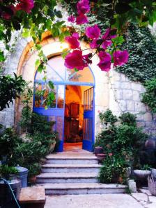 einen Eingang zu einem Haus mit einer blauen Tür und Blumen in der Unterkunft Mikes Khan in Abū Ghaush