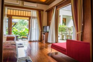 a living room with a red couch and a television at Villa Salika - SHA Plus in Rawai Beach