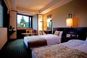 a hotel room with two beds and a window at Komagane Kogen Resort Linx in Komagane