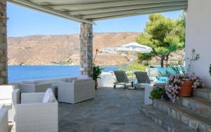 un patio con mobili bianchi e vista sull'acqua di Yperia Hotel ad Aegiali