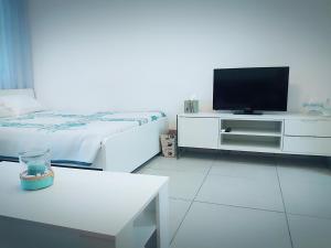 um quarto branco com uma televisão e uma cama em Billis Beach Apartment em Limassol