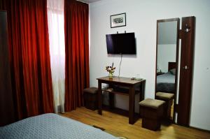 a bedroom with a bed and a desk with a television at Pensiunea Ana in Odoreu
