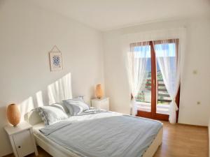 a white bedroom with a bed and a window at Sea View Apartments Nini in Vlašići