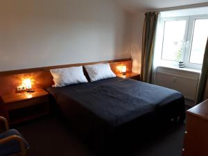 ein Schlafzimmer mit einem Bett mit zwei Nachttischen und einem Fenster in der Unterkunft Apartmentanlage Birdieweg in Hohen Wieschendorf