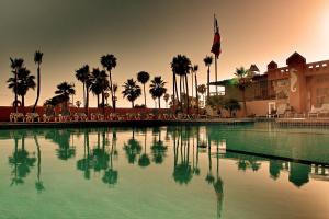 a large swimming pool with palm trees and a building at Hotel Villa Marina in Ensenada
